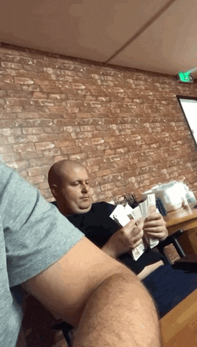 a man is sitting at a table holding a stack of money