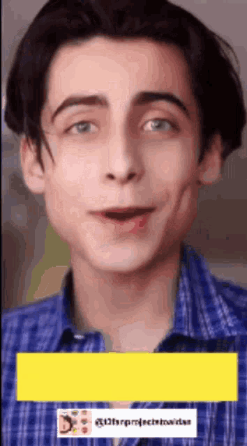 a young man wearing a blue plaid shirt is making a funny face with his mouth open .