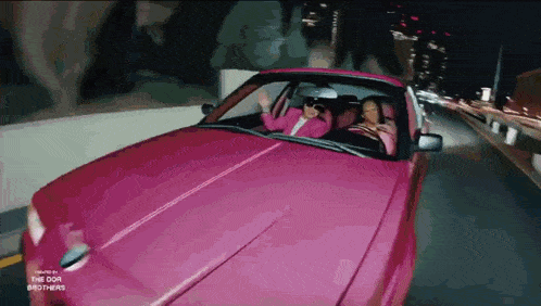 two people are driving a pink car which is sponsored by the doa brothers