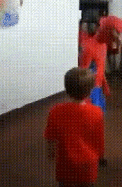 two young boys in red shirts are standing in a room .