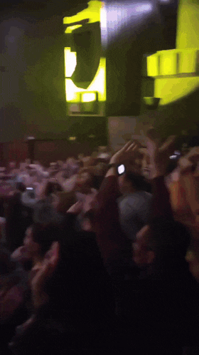 a crowd of people in a dark room with a yellow sign that says j on it