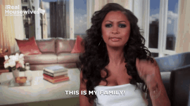 a woman says " this is my family " in front of a couch