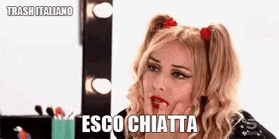 a woman with pigtails is looking at herself in a mirror and says esco chiata