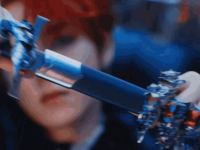 a close up of a person holding a blue and silver sword