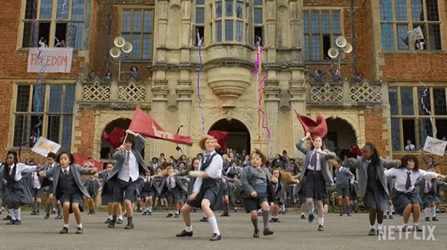 a large group of people are dancing in front of a building with a sign that says freedom