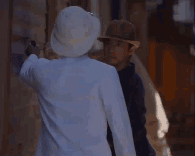 a man wearing a hat is standing next to another man wearing a white hat
