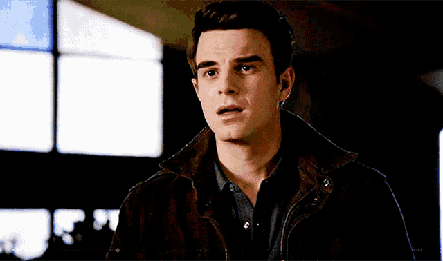 a young man wearing a brown jacket and a blue shirt