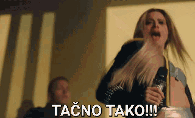a woman is singing into a microphone with the words tačno tako written below her