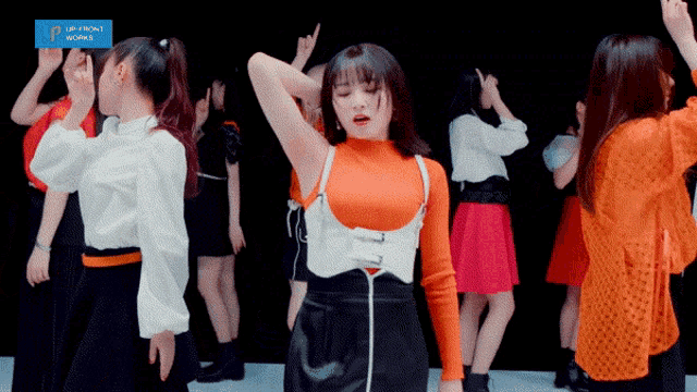 a group of young women are dancing in front of a sign that says up front works