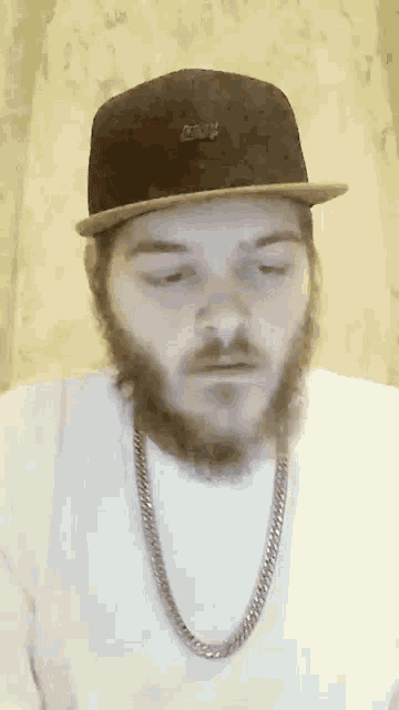 a man with a beard is wearing a hat and a chain around his neck