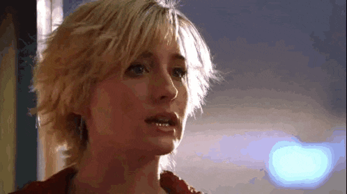 a close up of a woman 's face with short hair and a red jacket .