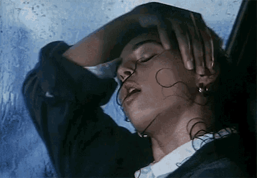 a close up of a woman 's face with her eyes closed and her hand on her head