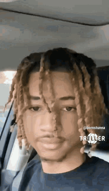 a man with dreadlocks is sitting in the back seat of a car .