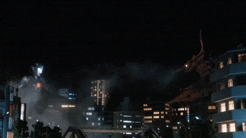 a blurred image of a city at night with a fire coming out of a building