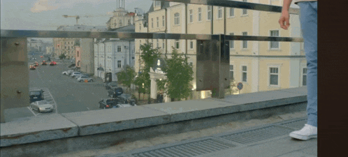 a person is standing on a balcony overlooking a city street