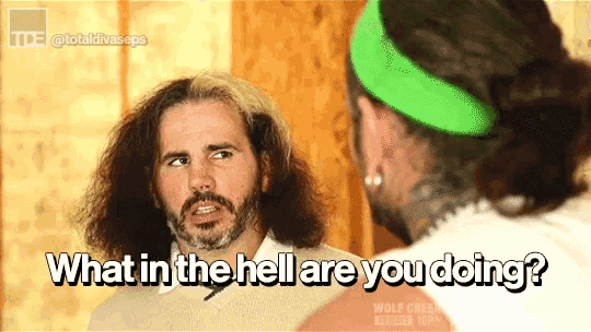 a man with long hair and a green headband is asking another man what in the hell are you doing ..