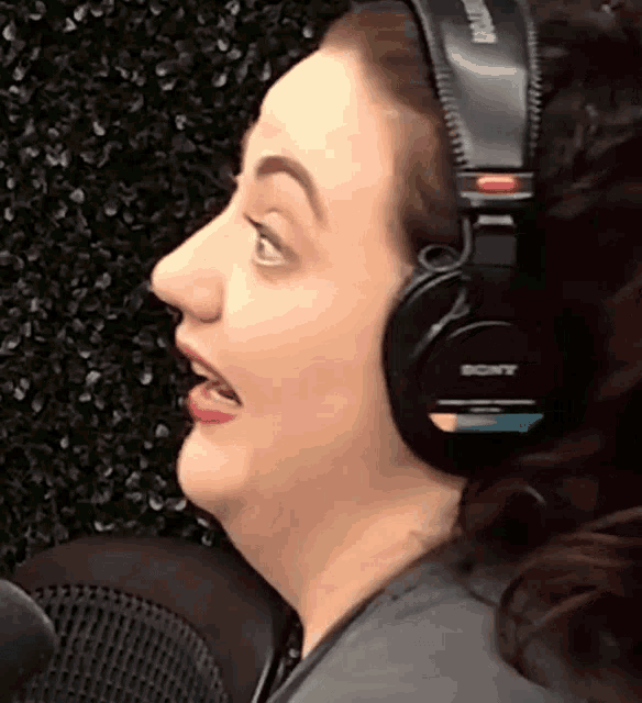 a woman wearing sony headphones is making a funny face