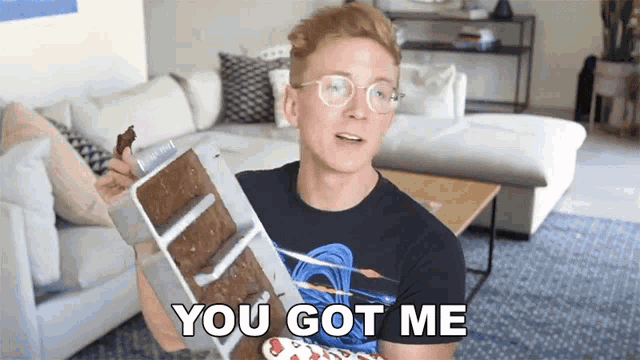 a man with glasses is holding a tray of brownies and says you got me