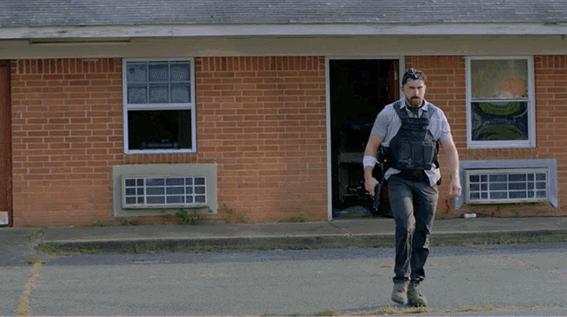 a man is running in front of a brick building with a huge explosion in the background