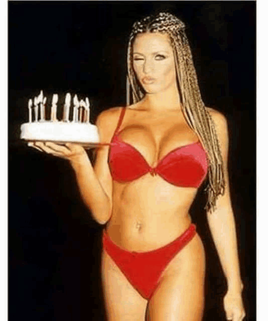 a woman in a red bikini is holding a birthday cake with candles .