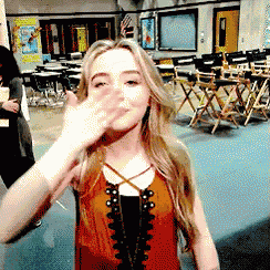 a girl covering her face with her hand in a room with chairs