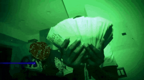 a man is holding a stack of 100 bills in his hands