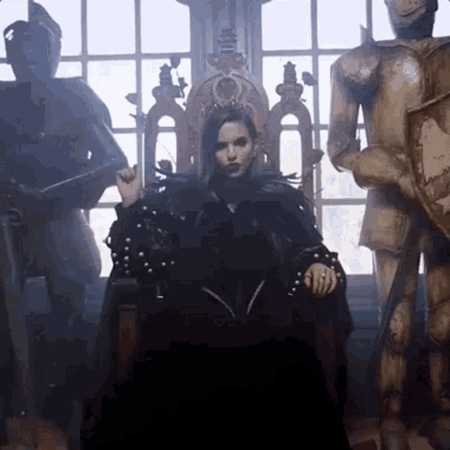 a woman in a black dress is sitting on a throne surrounded by statues of knights