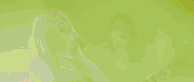 a person singing into a microphone with a green background