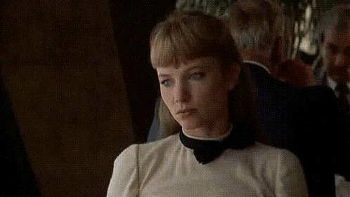 a woman is sitting in a dark room with the word no written on her face