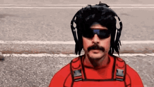 a man with a mustache wearing headphones and sunglasses is standing on the street .