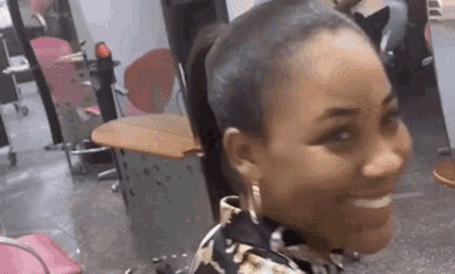 a woman is smiling in a hair salon while getting her hair cut .