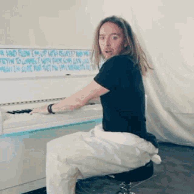 a man sits on a stool playing a piano
