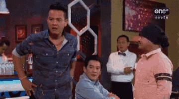 a group of men are standing and talking in a room .