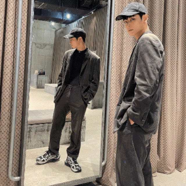 a man in a suit is standing in front of a mirror