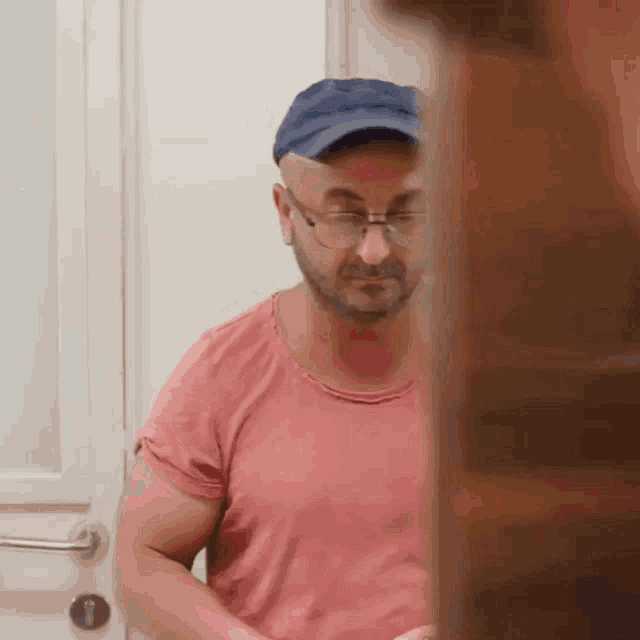 a man wearing glasses and a blue hat is standing in a doorway