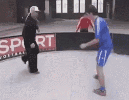 a man in a blue shirt and shorts is standing on a ice rink with a referee .