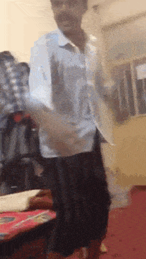 a man in a blue shirt and black shorts is dancing in a room