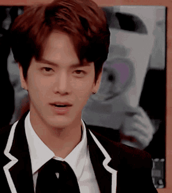 a young man wearing a suit and tie is looking at the camera
