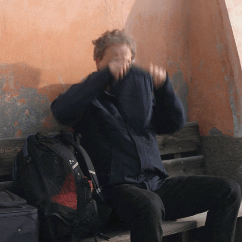 a man sitting on a bench with a backpack that says ' abercrombie & fitch ' on it