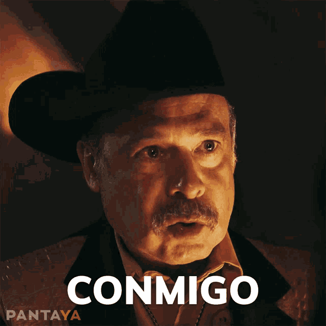 a man wearing a cowboy hat has the word conmigo on his face
