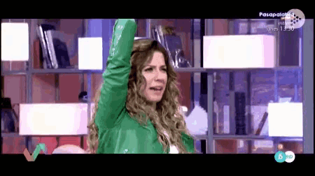 a woman in a green jacket is on a television screen