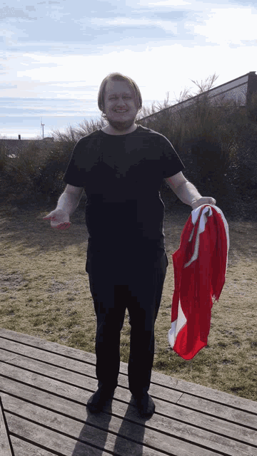 a man wearing a black shirt is holding a red and white flag