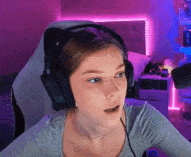 a woman wearing headphones is sitting in front of a microphone and making a surprised face .