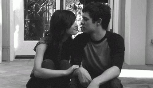 a black and white photo of a man and a woman kissing .
