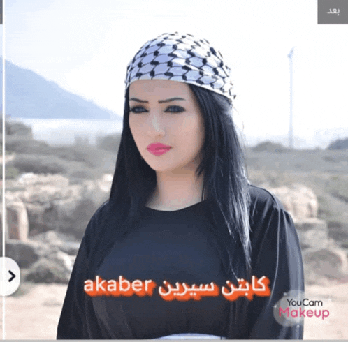 a woman wearing a head scarf and a black shirt with the words akaber on the bottom