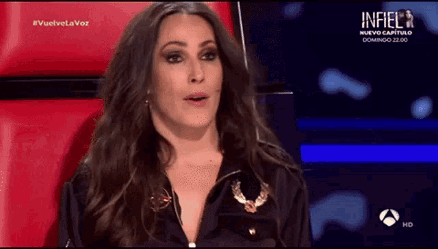 a woman is sitting in a red chair on a tv show called infiel .