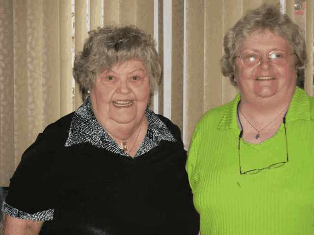 two older women posing for a picture with one wearing glasses
