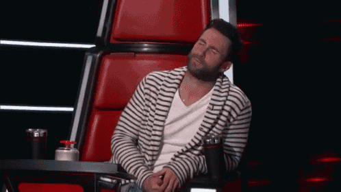 a man in a striped shirt is sitting in a red chair with his eyes closed