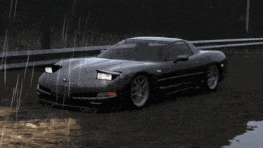 a black sports car is driving down a dirt road in the rain