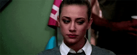 a close up of a woman 's face wearing a tie and sweater .